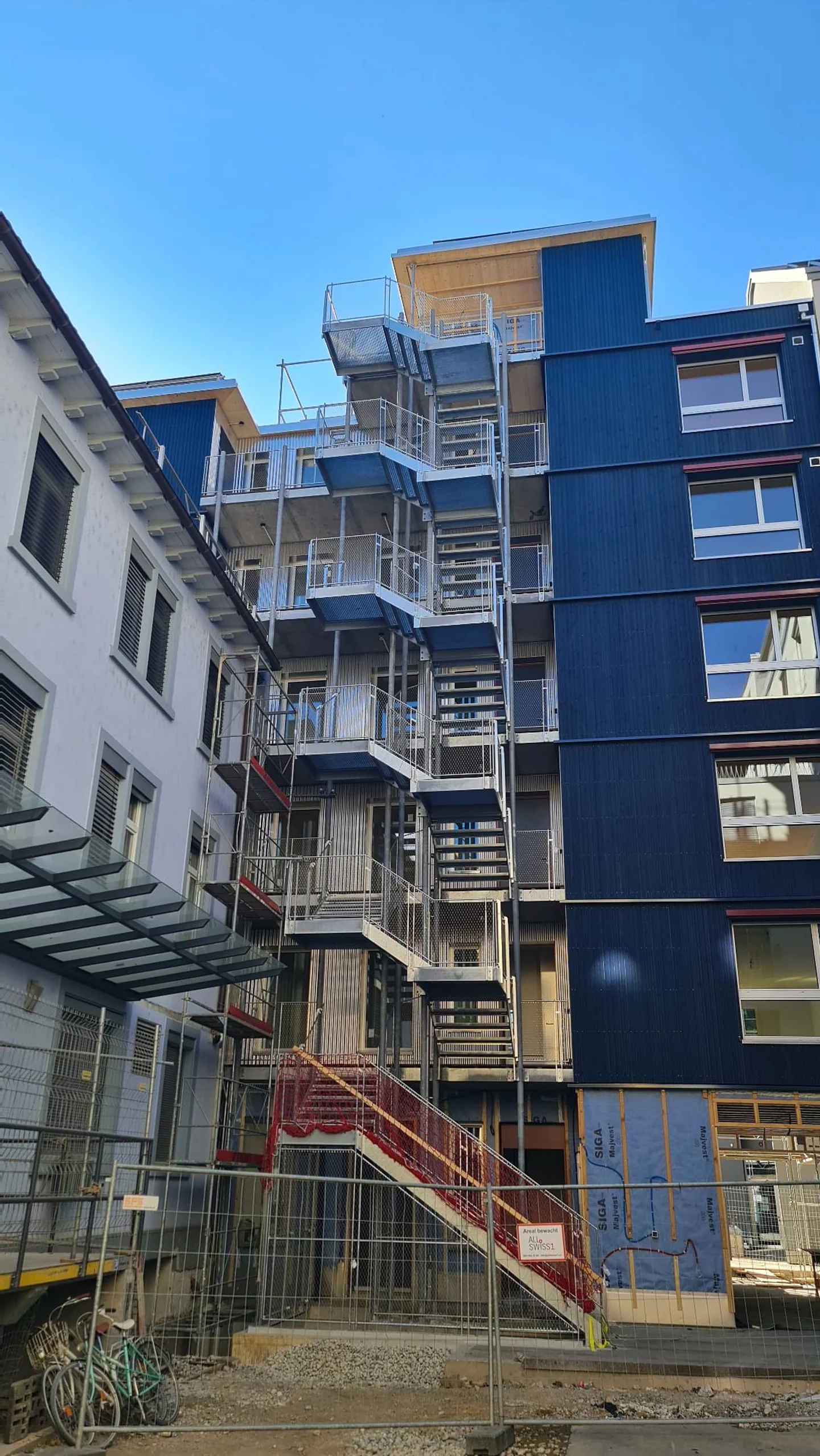 Aussentreppe über fünf Geschosse an einer blauen Holzfassade