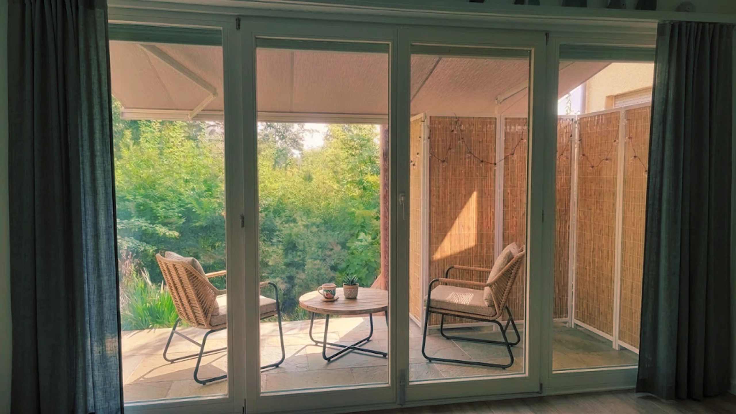 Raumhohe Verglasung zur Terrasse, von innen gesehen, mit Blick in den Garten
